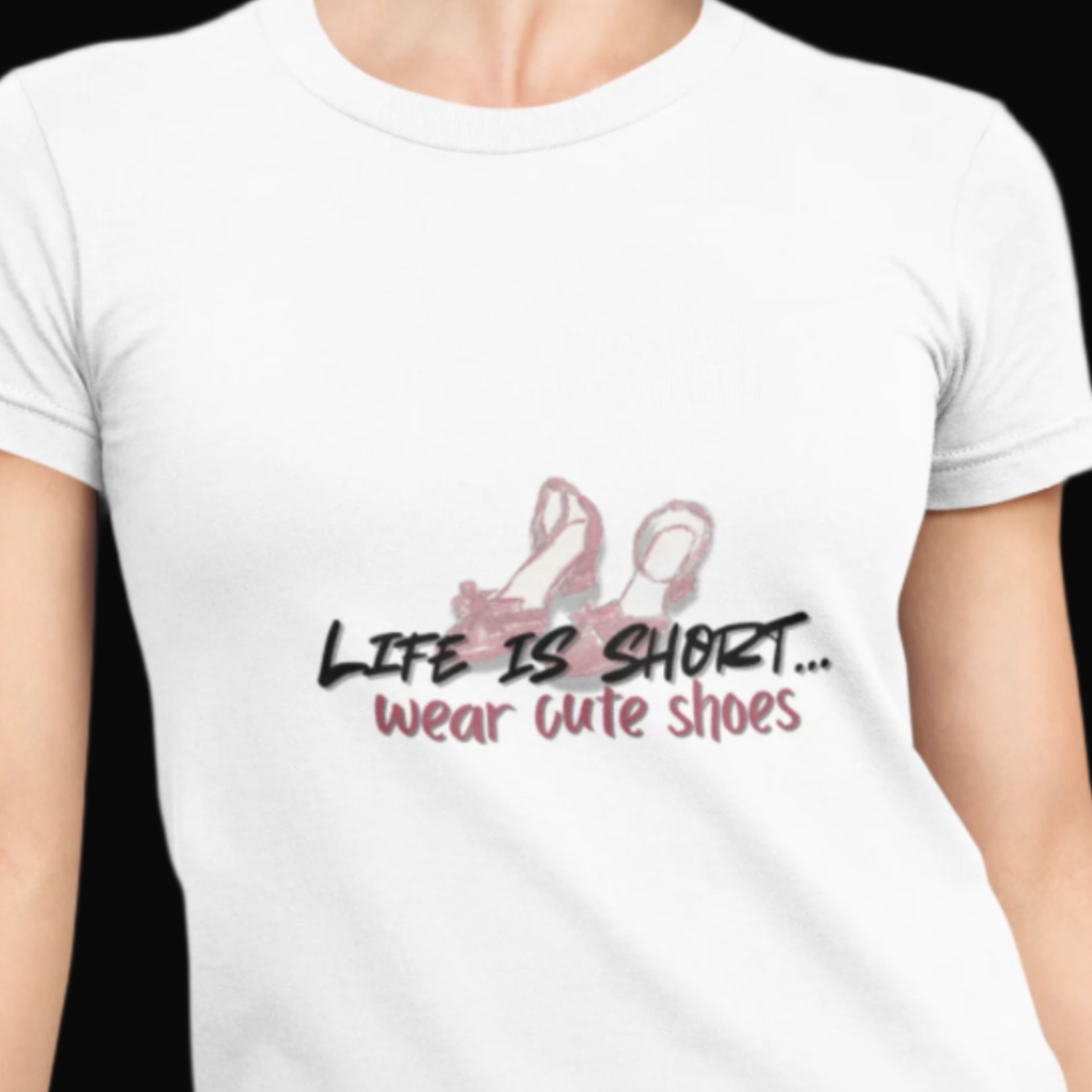White t-shirt with 'Life is short, wear cute shoes' text and flamingo graphic worn by a person.