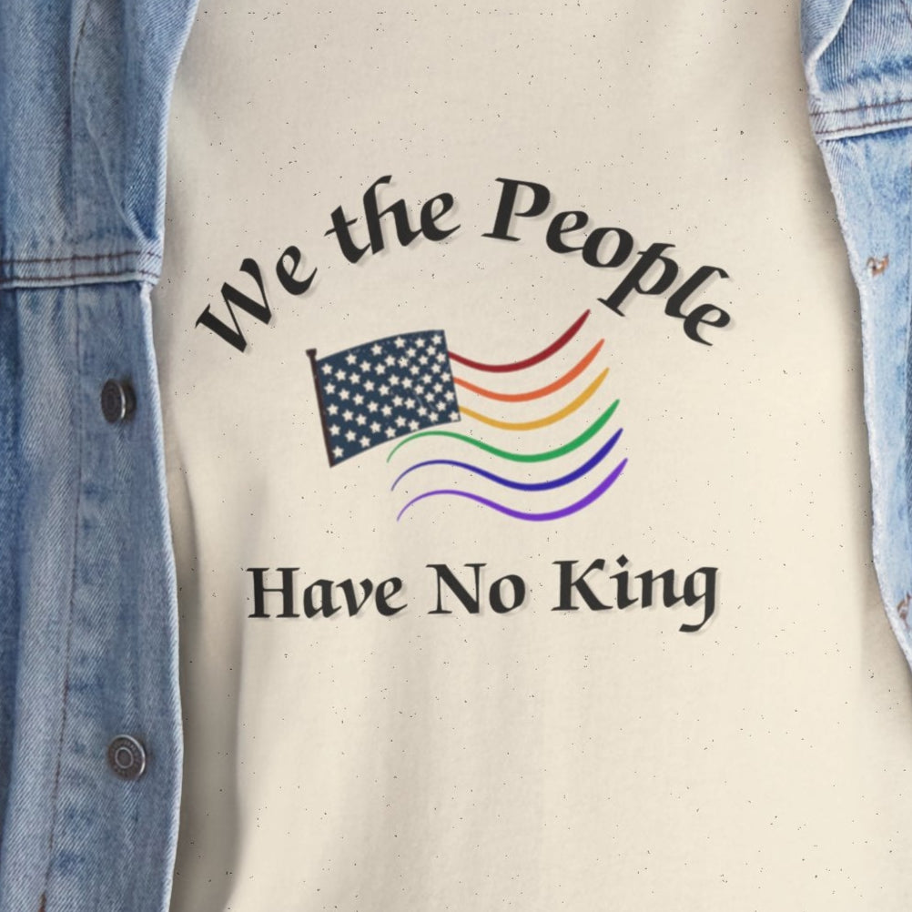 Person wearing a denim jacket over a shirt with 'We the People Have No King' text and rainbow flag design.