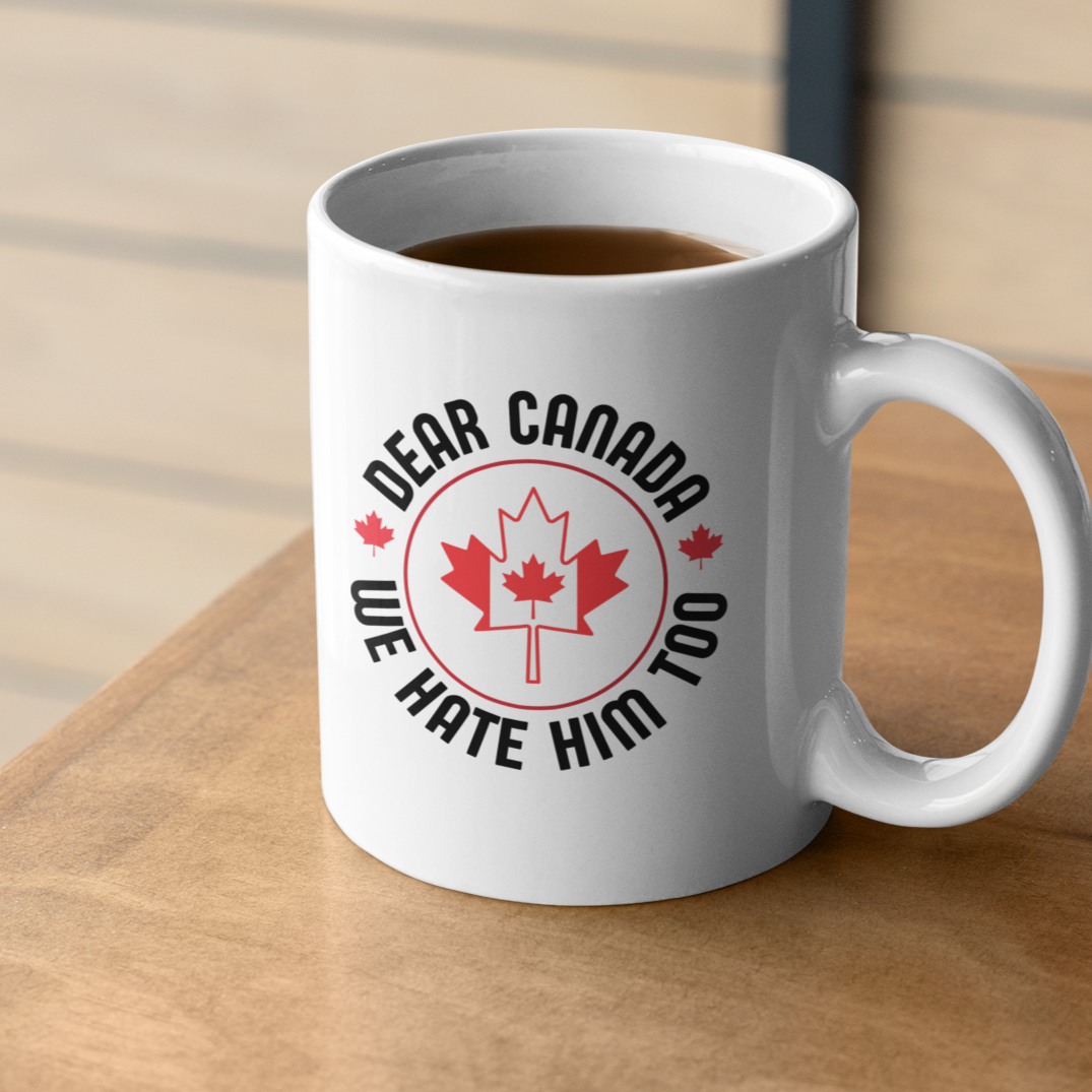 White mug with 'Dear Canada, We Hate Him Too' design on a wooden surface.
