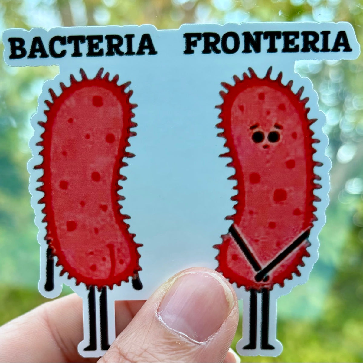 Bacteria Fronteria sticker held in hand outdoors